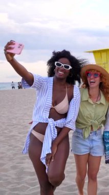 Çeşitli arkadaşlar plaj anılarını yakalıyor, gün batımında kumlu sahil şeridinde yürürken neşeli anları paylaşıyorlar.