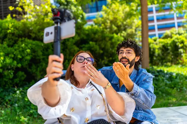 İki içerik yaratıcısı açık havada video kaydederken takipçilerine hava öpücüğü gönderiyor.