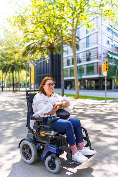 Mutlu kadın gözlük takıyor, elektrikli sandalye kullanıyor ve canlı şehir sokaklarını keşfederken güneşli bir günün tadını çıkarıyor.