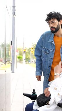 Kentsel hareketlilik desteği, genç adam elektrikli sandalye kullanarak kadınların sokaklarda dolaşmasına yardım ediyor, ulaşılabilirlik ve toplum gücünü gösteriyor.