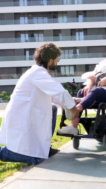 Doktor, tekerlekli sandalyedeki engelli bir kadının rahatlığı ve desteğini artırmak için ayak sehpasını dikkatlice ayarlar.