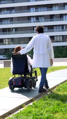 Profesyonel doktor taşınabilirlik yardımı sağlıyor, modern tıbbi tesisin dışında tekerlekli sandalyeli hastalara rehberlik ediyor, rehabilitasyon ve sağlık ihtiyaçlarını destekliyor.