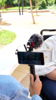 Sunny Park 'ta tekerlekli sandalye kullanıcısıyla iyimser bir röportaj yapan kadın gazeteci, profesyonel yaklaşımla kişisel hikaye ve engelli temsilciliğini yakalıyor.