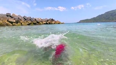 Mutlu turist berrak suyun tadını çıkarıyor, jestler yapıyor ve yaz tatilinde sahilde eğleniyor.