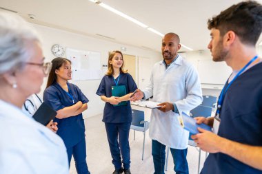 Doktorlar ve hemşireler tıbbi brifinge katılıyor, daha iyi bir hasta bakımı için fikir ve bilgi alışverişinde bulunuyorlar.