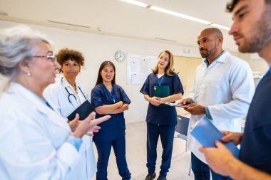 Hastane ortamında yapılan verimli bir toplantıda çeşitli tıp uzmanları işbirliği yapıyor, uzmanlık paylaşıyor ve hasta bilgilerini gözden geçiriyorlar.