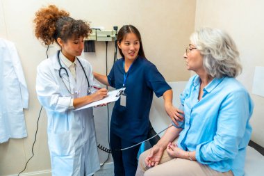 Yaşlı kadınların sağlığıyla ilgilenen tıp uzmanları, klinikteki sağlık muayenesi sırasında kan basıncı kontrolü yapıyorlar.