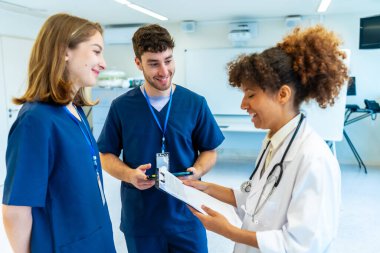 Doktorlar ve hemşireler işbirliği yapıyor, tıbbi kayıtları analiz ediyor ve hastane ortamında hasta tedavisini tartışıyorlar.