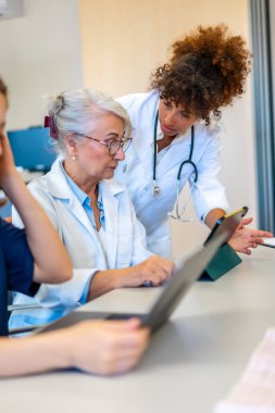 Tıp uzmanları bir tablet üzerinde işbirliği yapıyor, hasta vakalarını tartışıyor ve hastane toplantılarında uzmanlıklarını paylaşıyorlar.