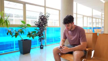 Hastane üniformalı bir tıp uzmanı klinikte bekleyen bir hastayı arıyor, sağlık kontrolü ve sağlık kontrolü için akıllı telefon kullanımını kesiyor.