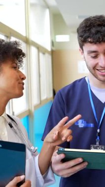 Doktorlar ve hemşireler dijital tablete danışarak hastane ortamında bilgi ve uzmanlık alışverişinde bulunurlar.