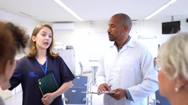 Sağlık uzmanları işbirliği yapıyor, parlak hastane konferans odasında hasta tedavi stratejisini tartışıyor, tıbbi görüşlerini odaklanmış bir şekilde paylaşıyorlar.