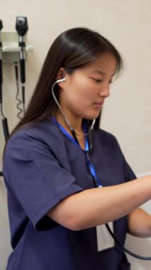 Klinikteki tıbbi muayene sırasında yaşlı kadın hastaların ciğerlerini steteskopla muayene eden genç bir kadın doktor.