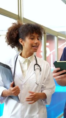 Doktorlar ve hemşireler tıbbi kayıtları inceliyor ve hastane koridorunda hasta vakalarını tartışıyorlar.