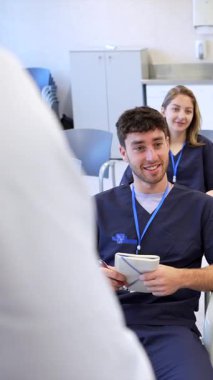 Deneyimli bir eğitmen liderliğindeki bir eğitim oturumuna, klinik bir ortamda takım çalışmalarını ve öğrenmeyi ön plana çıkaran çeşitli sağlık uzmanları katılır.