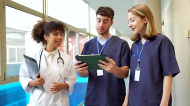 Doktorlar ve hemşireler bir tabletin tıbbi kayıtlarını inceliyor. Verimli iletişim ve işbirliği yoluyla hasta bakımını geliştiriyorlar.