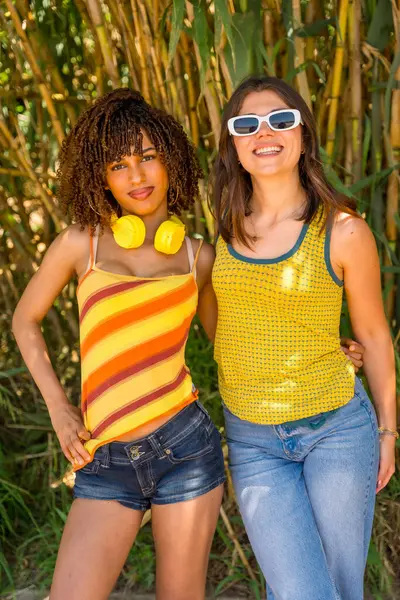 Bereketli bir bambu ormanında poz veren iki bayan arkadaş, güneşi emerek canlı bir yaz gününün neşesini kucaklıyorlar.