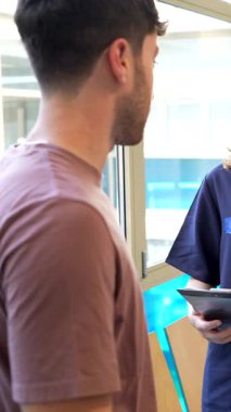 Uzman hemşire hasta bilgilerini doktorla paylaşıyor. Parlak hastane ortamında tıbbi bilgileri gözden geçirip şefkatli sağlık desteği sağlıyor.