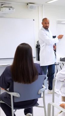 Tıp öğrencileri profesörlerinin derslerini dikkatle dinliyor ve bir üniversite sınıfı sırasında tartışmalara giriyorlar.