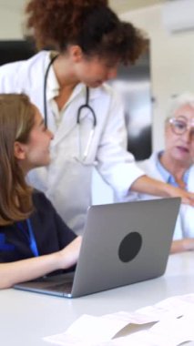 Doktorlar ve hemşireler, modern bir tıbbi ortamda dizüstü bilgisayarlar ve tabletler kullanarak uzmanlık ve bilgi paylaşımı yaparak işbirliği yaparlar.