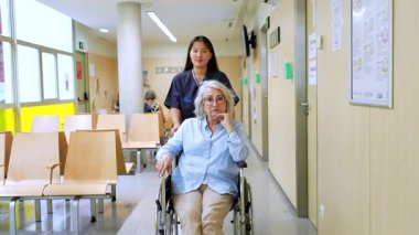 Merhametli hemşire, tekerlekli sandalyedeki yaşlı hastalara hastane koridorunda rehberlik ediyor ve profesyonel sağlık hizmeti sunuyor.