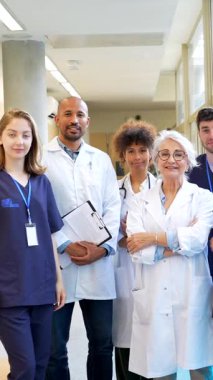 Doktorlar ve hemşireler de dahil olmak üzere bir grup sağlık uzmanı, hastane koridorunda işbirliği yaparak tıbbi alanda takım çalışması ve çeşitliliği temsil ediyorlar.