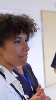 Deneyimli kadın doktor, hemşire ekibine hastane koridorunda hasta bakımı hakkında brifing veriyor.