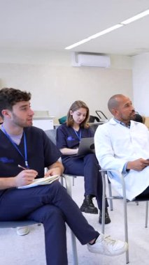 Doktorlar ve hemşireler bir tıp konferansına aktif olarak katılıp sunumu dikkatle dinliyorlar.