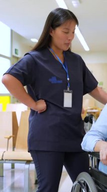 Hemşire, sağlık merkezinde tekerlekli sandalyede oturan yaşlı bir kadınla ilgileniyor. Sakin ve profesyonel bir ortamda bakım ve destek sağlıyor.