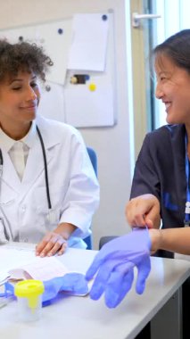 Klinik iş ortamında yapılan işbirliği sırasında koruyucu eldiven giyen tıp uzmanları bilgi alışverişinde bulunuyorlar