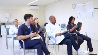 İleri düzey eğitim oturumuna katılan profesyonel tıp ekibi, hastane sınıfındaki dijital teknolojiyi kullanarak işbirliği yaparak yeni prosedürler öğreniyor.