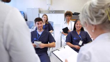 Çeşitli tıp öğrencileri, bir hastane eğitiminde kıdemli doktorların verdiği dersi dikkatle dinliyor.