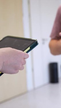 Sınava ya da sunuma hazırlanmak için sınıfta öğretmenden tablet alan asabi öğrenci