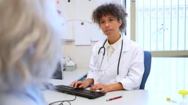 Doktor bir hastayla dikkatlice iletişim kurar ve klinik bir ortamda tıbbi tavsiyelerde bulunur. Profesyonel sağlık diyaloğu