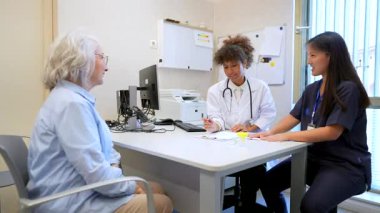 Doktor ve hemşire yaşlı hastalarla iletişim kuruyor, hastane ortamında tıbbi danışmanlık ve bakım sağlıyorlar.