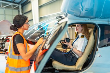 Uçak bakım müfettişi kadın pilotla konuşurken not alıyor. Uçuş için hazırlanıyor.