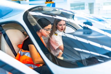 İki kadın pilot, biri üniformalı, diğeri de güvenlik yelekli, bir uçak kokpitinde işbirliği yapıyorlar, uçuş kontrollerine odaklanıyorlar.