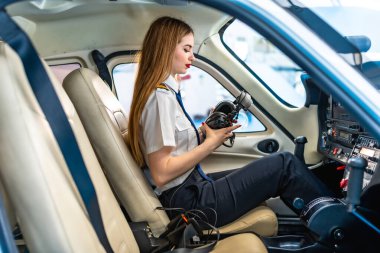 Küçük bir uçağın kokpitinde otururken kulaklığını kontrol eden genç kadın pilot, uçuşa hazırlanıyor.