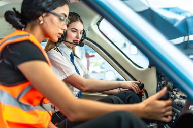 Küçük bir uçağın kokpitinde çalışan kadın pilot ve mühendis kalkışa hazırlanıyor.