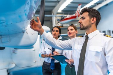 Bakım ekibi hangardaki uçak kanadını inceliyor. Uçuş güvenliği ve operasyonel verimliliği sağlıyorlar.