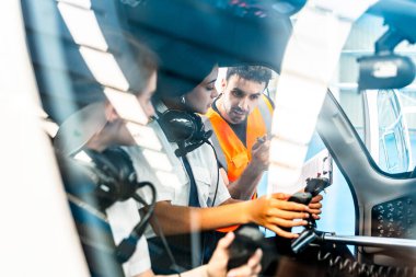 Eğitmen kokpit simülatöründe uçuş eğitimi sırasında iki pilot öğrenciye uçak kontrollerini açıklıyor.