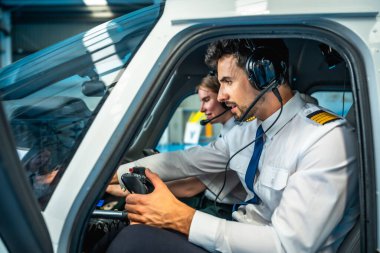 İki erkek pilot uçuş simülatörünün kokpitinde oturuyorlar, kulaklık kullanıyorlar ve kontrolleri tutuyorlar, eğitimdeler.