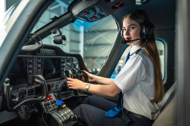 Modern bir uçağın kokpitinde oturan genç bayan pilot kontrolleri ayarlıyor ve kalkışa hazırlanıyor.