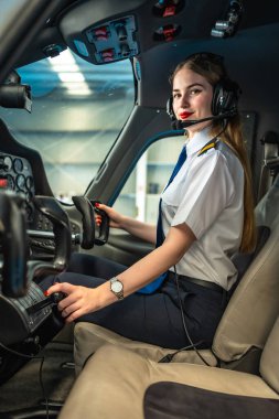 Küçük bir uçağın kokpitinde oturan kendinden emin kadın pilot kontrolleri ayarlıyor ve uçuş için hazırlanıyor.