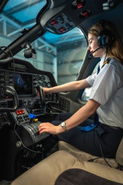 Pilot kabini içinde modern bir uçağın kontrollerini ustalıkla yapan kendine güvenen kadın pilot, havacılıkta uzmanlık ve profesyonellik gösteriyor.