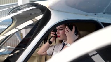 Kendine güvenen kadın pilot kalkışa hazırlanıyor, kulaklığını ayarlıyor ve küçük bir uçağın kokpitinde iletişim kuruyor.