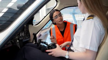 Kadın uçuş eğitmeni küçük bir uçağın kokpitindeki stajyer pilota uçak kontrollerini anlatıyor.