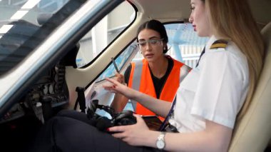 Havacılık kulaklığı takan bayan pilot pilot uçak kokpitinde uçuş öncesi rehberliği alıyor, eğitim sırasında profesyonel odaklanma gösteriyor.