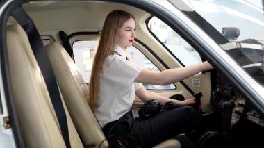 Kadın pilot uçuş için hazırlanıyor, uçak kokpitindeki kontrolleri ve iletişim sistemlerini ayarlıyor