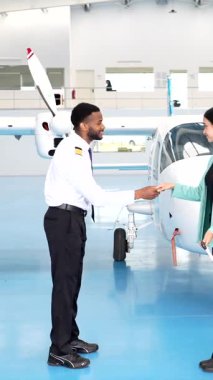 Şirket yolcuları pilotu sıcak bir şekilde selamlıyor, modern havacılık hangarından küçük özel bir uçağa binmeden önce el sıkışıyorlar.